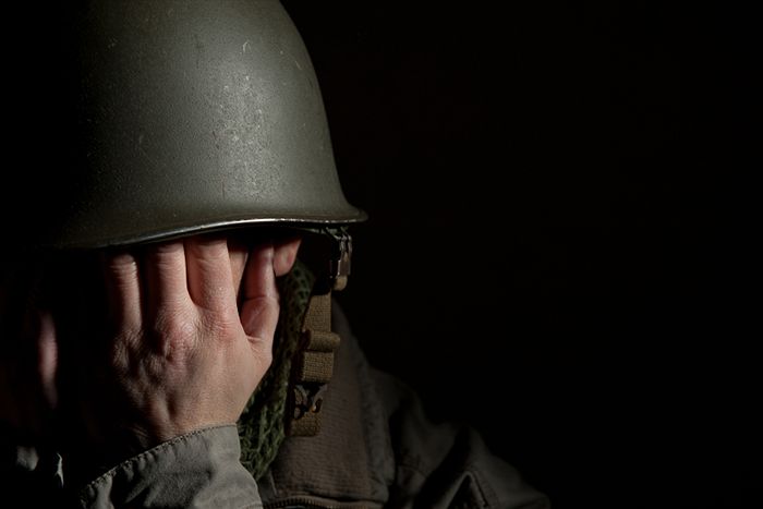 A soldier in fatigues and helmet covering his face.