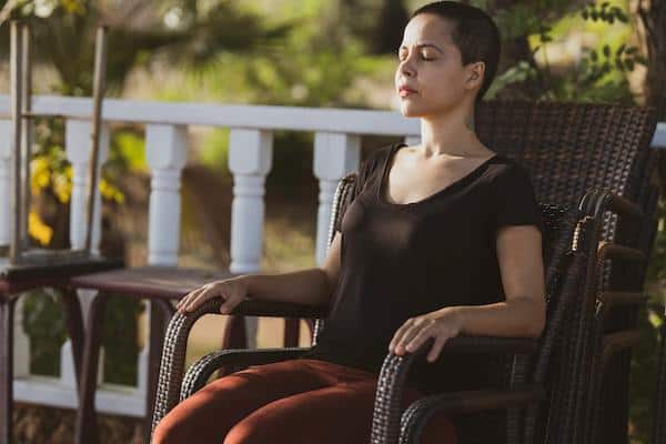 woman meditating outdoors on chair