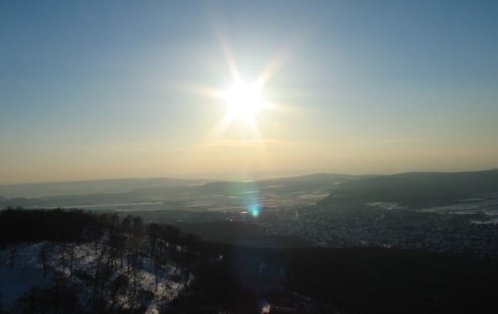 A sun setting over the mountains with snow on top.