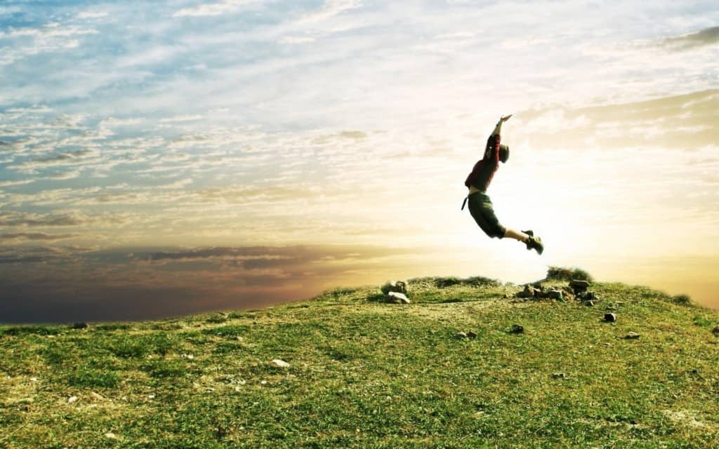 A man jumping in the air on top of a hill.