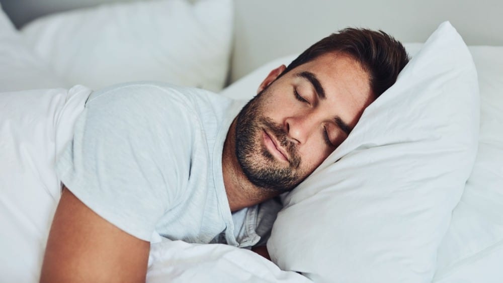 A man sleeping in bed with his eyes closed.