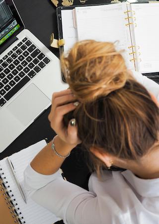 woman at messy desk with head in hands