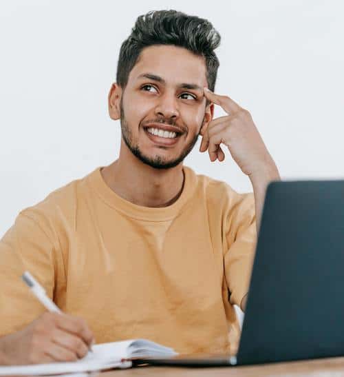 man smiling while writing in notebook
